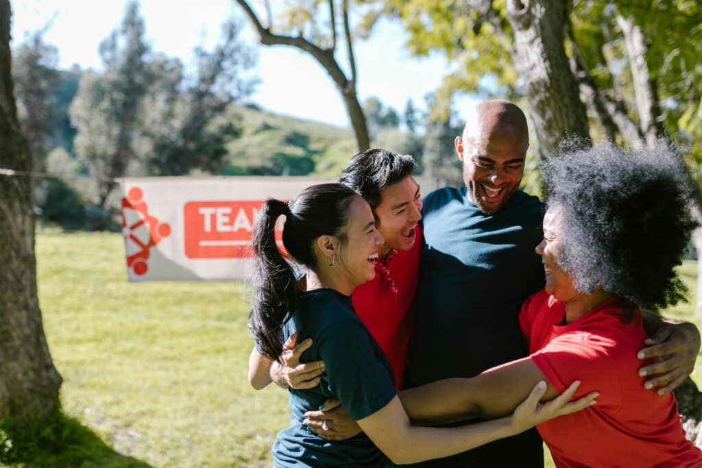 A joyful group of friends embracing in a team building event outdoors.